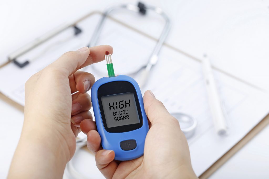 hand-holding-blood-glucose-meter-measuring-blood-sugar-background-is-stethoscope-chart-file-1